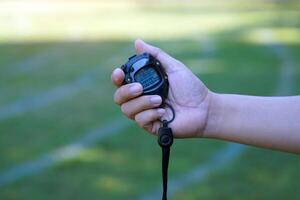 coach timed the finish line with a stopwatch to determine the winner of the school sports day running event. soft and selective focus. photo