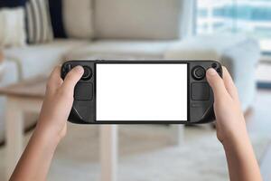 Flat lay or front view of hands holding a black handheld gaming console with isolated screen, cozy living room background, ideal for mockup game presentation and design photo