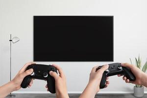 Two players holding gamepad in front of a TV with a blank screen, designed for game promotion and mockup presentations photo