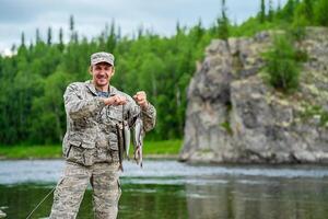 Fisherman With His Catch Of Fish Against The Backdrop Of A Rock photo