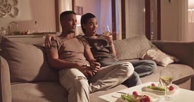 Diverse couple watching TV during date video