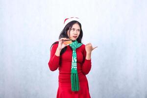 asian ladies happy to camera hand holding credit debit card and sweater, sarcasm left hand holding credit debit card and pointing left, isolated on white background photo