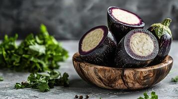 A bowl of purple eggplant with a slice cut out photo