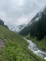 A river runs through a green valley surrounded by mountains photo
