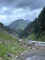 A man standing on the bank of a river in the mountains photo