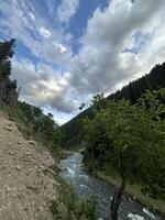 A dirt road leading to a river in the mountains photo