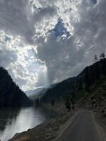 A road leading to a river with clouds in the sky photo