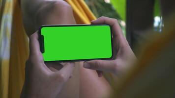 A person holding a phone with a green screen background, ideal for showcasing mobile apps, digital marketing, or phone-related projects. video