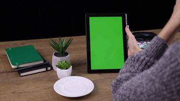 A woman using a tablet with a green screen, ideal for showcasing digital applications, tech interactions, or mobile content creation in a professional or casual setting. video