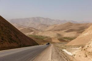 Desolate landscape along a winding road in Faryab Province, Afghanistan during daylight hours photo