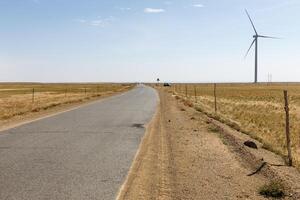 asphalt road in the steppe with wind generator on the horizon, Inner Mongolia photo