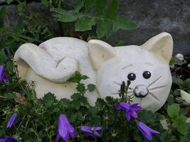 Cute Stone Cat Sculpture Amidst Purple Flowers in Garden photo