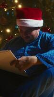 Man With Blue Pajamas Enjoys Advent Calendar Near Christmas Tree At Night video