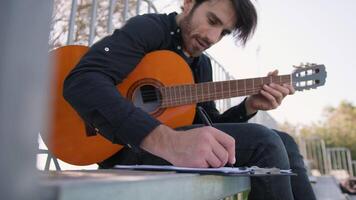 joven compositor escribe notas en Puntuación a jugar con clásico guitarra video