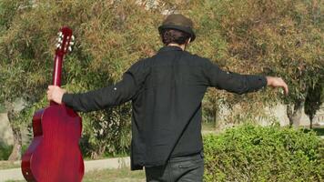 Man In Black Suit Walks Hovering With His Classical Guitar In His Hand video