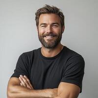 A headshot of a smiling, lights man with brown hair and a beard. The background is a plain gray. photo