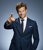 A handsome man in a navy blue suit smiles confidently, pointing directly at the viewer photo