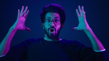 Male portrait neon ultraviolet background Arabian man Indian guy coder hacker showing head mind explosion gesture boom brainstorm idea mental shock information think computer technology sci-fi future photo
