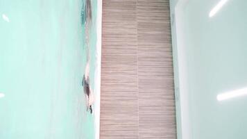 Swimmer gliding gracefully through turquoise pool in minimalist indoor setting captures dynamic movement and serene atmosphere. video