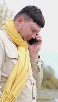 young caucasian man walking in the park and using smartphone, having a call video