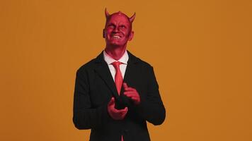 Red devil businessman clapping hands on orange background video