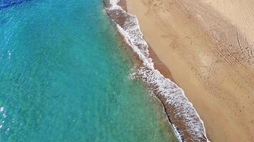 Turquoise water gently lapping the golden sand of a pristine beach in mersin, turkey. The sun's reflection dances on the water's surface video