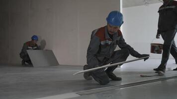 Workers in uniform and safety helmets lay tiles in a house under construction video