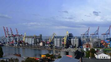 Time lapse view of industrial port and container loaders. Port landscape with moving shore cranes and grain elevators under clouds floating in blue sky video
