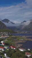 Aerial view of picturesque fishing town of Reine on Lofoten islands in Norway, popular tourist destination on sunny summer day, vertical footage video