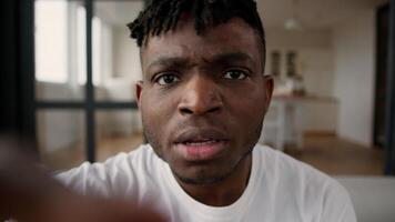 African man guy POV using mobile phone touchscreen scrolling screen social media male blogger influencer gadget addict browsing internet at home typing display confused upset shock read news disgust video
