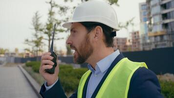 Caucasian angry mad negative aggressive architect engineer contractor repairman in city shouting screaming building urban development industry man in helmet hardhat yelling on walkie talkie problem photo