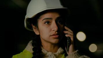 Young professional arabian woman technical engineer builder architect in uniform and hardhat talking mobile phone with building worker discussing working process supervising construction on parking photo