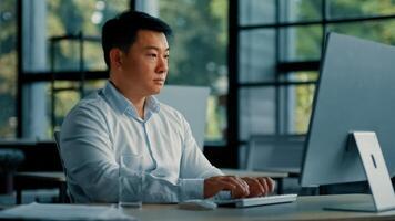 Professional male worker asian korean man successful businessman programmer specialist sit at office desk work with computer software program freelance online job business commerce typing on keyboard photo