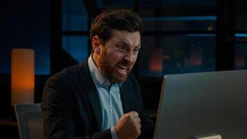 Annoyed angry businessman Caucasian middle-aged 40s man CEO employee mad furious crazy shouting fail online business project on computer trouble failure problem stress evening night office background photo