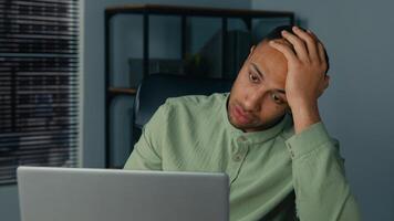 Desperate frustrated stressed african american man receive bad news by email on laptop in office evening sad worried shocked male businessman employee browsing computer crash error problem fail online photo