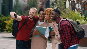 Happy smiling posing multiracial students diverse multiethnic friends university college campus outdoors after studying make selfie photo photography with mobile phone shooting hugging high five
