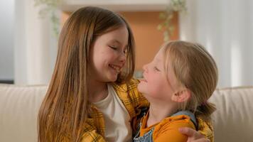 Portrait happy cute little caucasian girls children sisters kids friends smiling look at each other hugging embracing cuddle looking camera family love care affection relationship embrace hug indoors photo