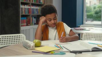School classroom studying African American kid little boy son schoolboy pupil learner student tired sleepy child yawning learn lesson boring homework write test exam at desk study primary education video