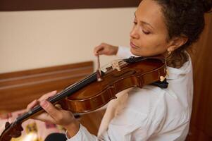 Woman practicing violin with focus on technique in a cozy room photo
