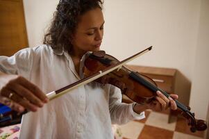 Person practicing violin in a cozy room, focused on music and technique photo