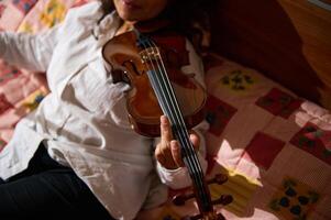 Close-up of person playing violin while relaxing on a colorful quilt photo