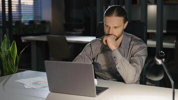 Caucasian businessman at office workplace with laptop working thinking strategy analyzing data business man company employer entrepreneur work computer pensive think idea problem solution difficulty photo