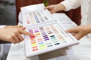 Women enjoy a pampering session at a salon, discussing nail color options. One woman points to the color chart, while the other considers various fashionable shades. photo