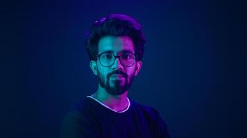 Portrait Indian serious man developer coding worker programmer profile looking to side turn head internet technology hacker male in glasses in blue ultraviolet studio background high-tech cyberspace photo
