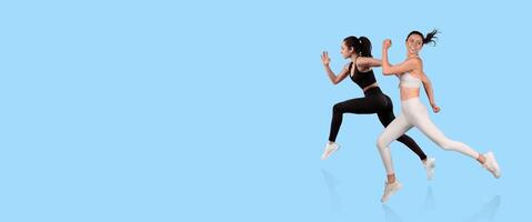 Two women are running at a fast pace with determination. They wear coordinating athletic attire and appear to be enjoying an invigorating fitness activity in a vibrant environment. photo