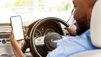 Back rear over the shoulder view of happy black male driver holding smartphone with white blank screen, mock up. Closeup of cellphone with empty display, guy using mobile app for navigation, copyspace photo