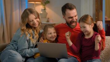 Family mother father children Caucasian parents kids little girls daughters on home couch evening weekend using laptop online shopping watch movie computer addict play game lose fail upset sad photo