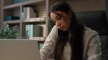 Caucasian businesswoman talking phone typing laptop multitask in office business girl woman using computer answering call talk smartphone consult client conversation on cell while working with online photo