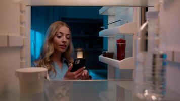 Point of view POV inside refrigerator Caucasian girl hungry woman open fridge at home kitchen look at empty shelves order food products delivery with mobile phone app online service web store shopping photo