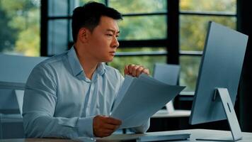 Desperate sad asian japanese senior specialist businessman sit at office read documents scam notification error in business documentation man research paperwork incorrect data upset about debt problem photo